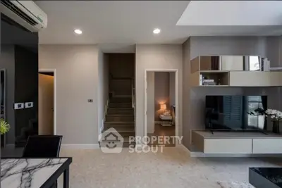 Modern living room with sleek TV unit and staircase leading to upper floor