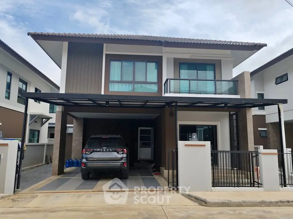 Modern two-story house with carport and balcony in suburban neighborhood.