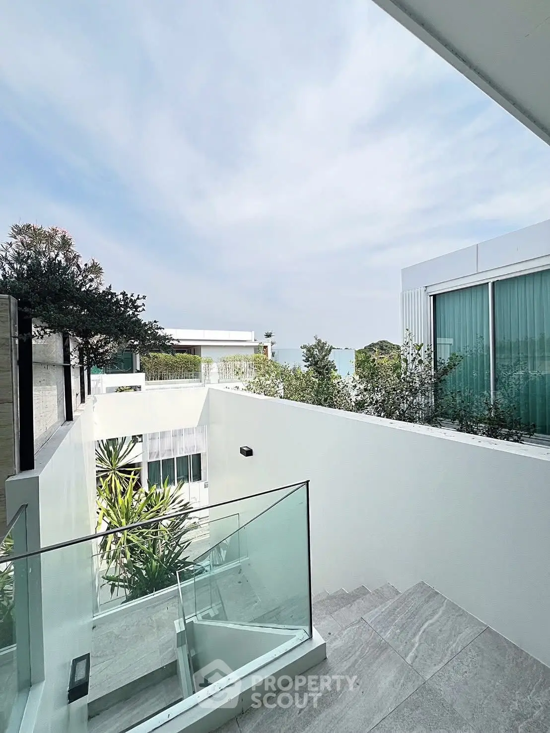 Modern architectural exterior with glass railings and lush greenery