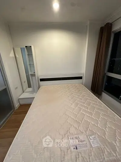 Cozy bedroom with large window and modern furnishings in a high-rise apartment.