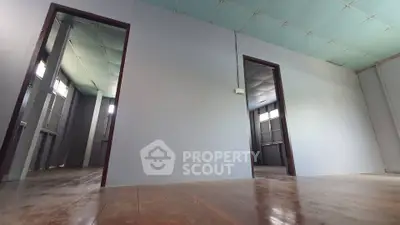 Spacious empty room with wooden floors and multiple doorways, ideal for customization.