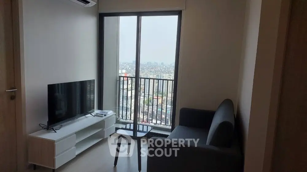 Modern living room with city view from balcony, featuring sleek furniture and natural light.