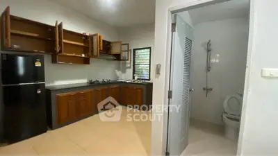 Spacious kitchen with wooden cabinets and adjacent bathroom in modern home