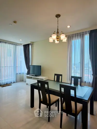 Spacious living room with elegant dining area and large windows offering natural light.