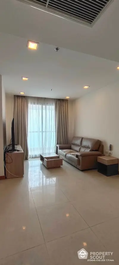 Spacious living room with glossy tiled flooring, modern furniture, and abundant natural light from floor-to-ceiling windows draped with elegant curtains.