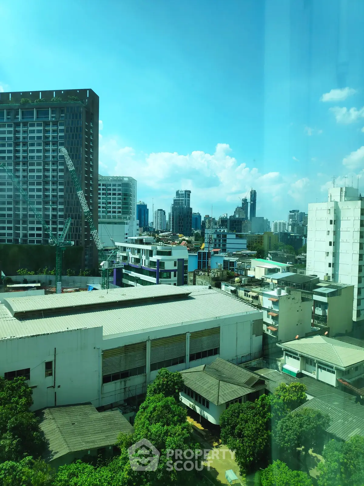 Stunning cityscape view from high-rise building with lush greenery and urban skyline.