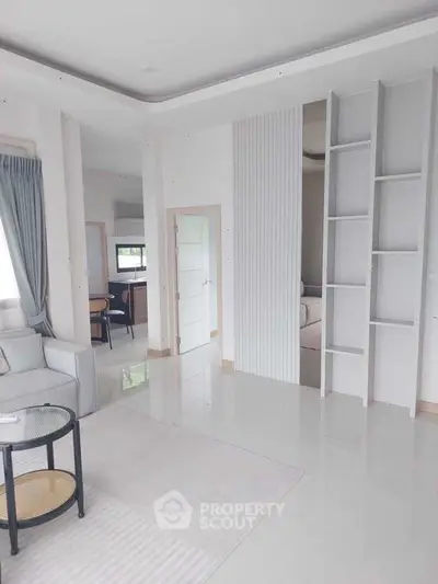 Modern living room with sleek design and open layout, featuring a cozy seating area and stylish shelving.