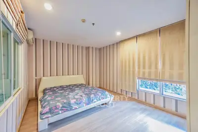 Spacious bedroom with stylish striped wallpaper and large windows for natural light.