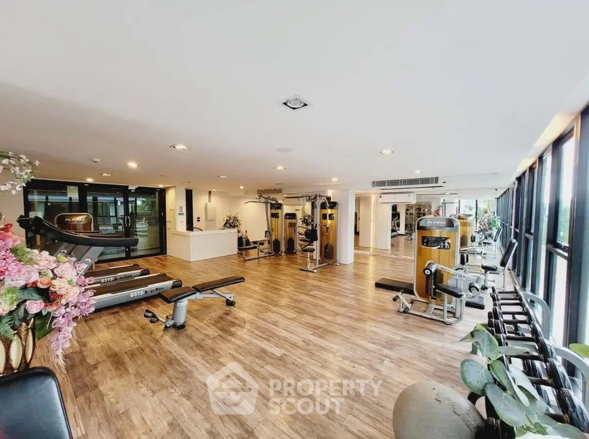 Spacious modern gym with state-of-the-art equipment and large windows for natural light.