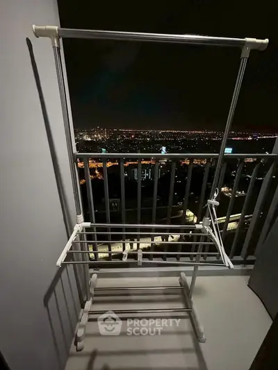 Stunning night cityscape view from a high-rise balcony with a drying rack.