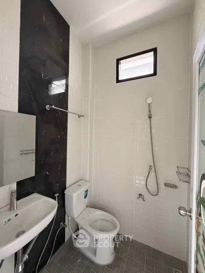 Modern bathroom with sleek fixtures and stylish black accent wall, featuring a shower and toilet.