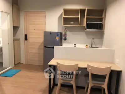 Modern compact kitchen with dining area and sleek appliances in cozy apartment.