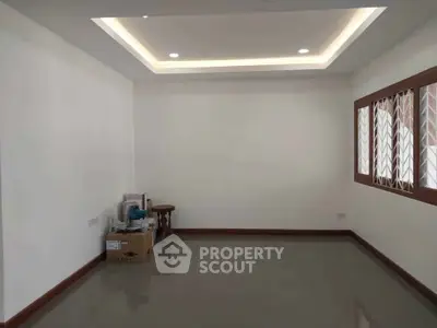 Spacious unfurnished room with modern ceiling lights and large window, ideal for customization.
