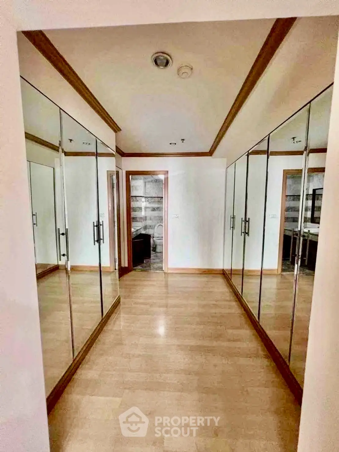 Spacious walk-in closet with mirrored doors and wooden flooring in modern home.