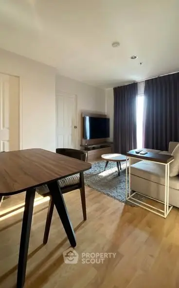 Modern living room with wooden flooring, stylish furniture, and a large TV, perfect for relaxation.