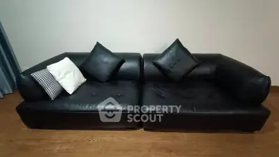 Elegant black leather sofa with cushions in a modern living room setting.