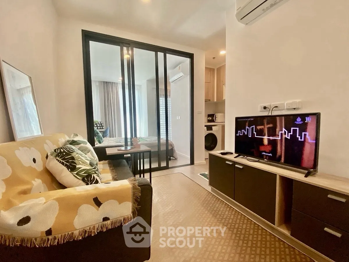 Modern living room with cozy sofa and TV, open layout to bedroom.