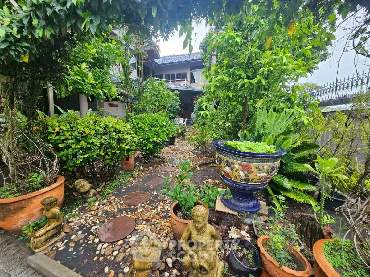 Charming garden with lush greenery and decorative statues in a serene residential setting.