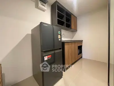 Modern kitchen with sleek fridge and wooden cabinets in a compact layout.