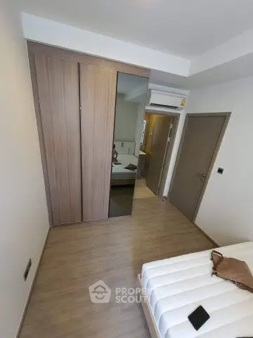 Modern bedroom with wooden flooring and built-in wardrobe, showcasing minimalist design.