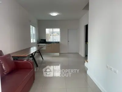 Spacious open-plan living area with modern kitchen and sleek tile flooring.