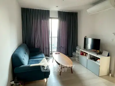 Cozy living room with modern sofa, TV, and natural light from balcony.