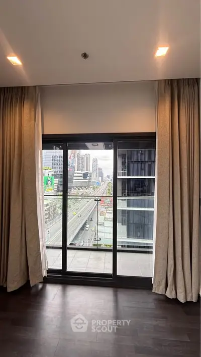 Modern apartment with floor-to-ceiling windows offering stunning city views and elegant curtains.
