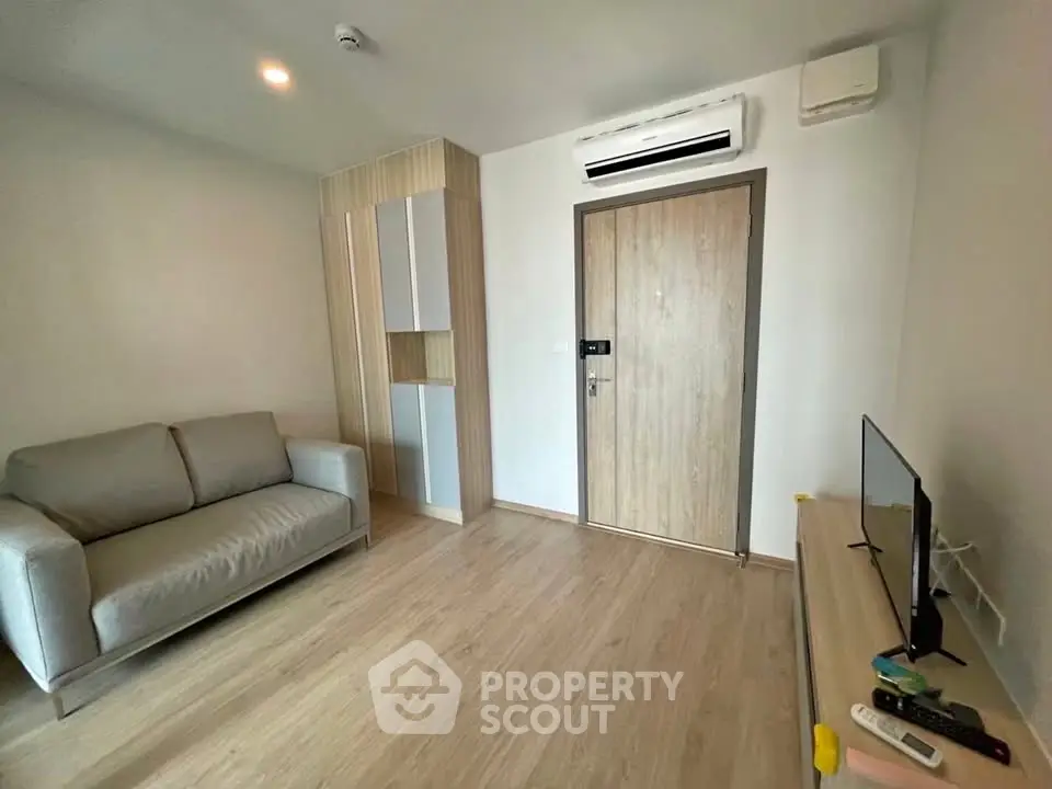 Modern living room with sleek design, featuring a cozy sofa and wall-mounted air conditioning.