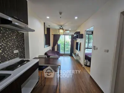 Modern open-plan living room with kitchen and balcony view, featuring stylish decor and ample natural light.