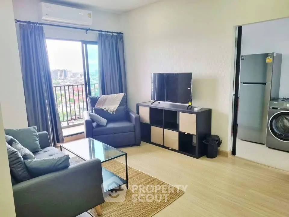 Modern living room with balcony view, sleek furniture, and adjacent kitchen area in urban apartment.