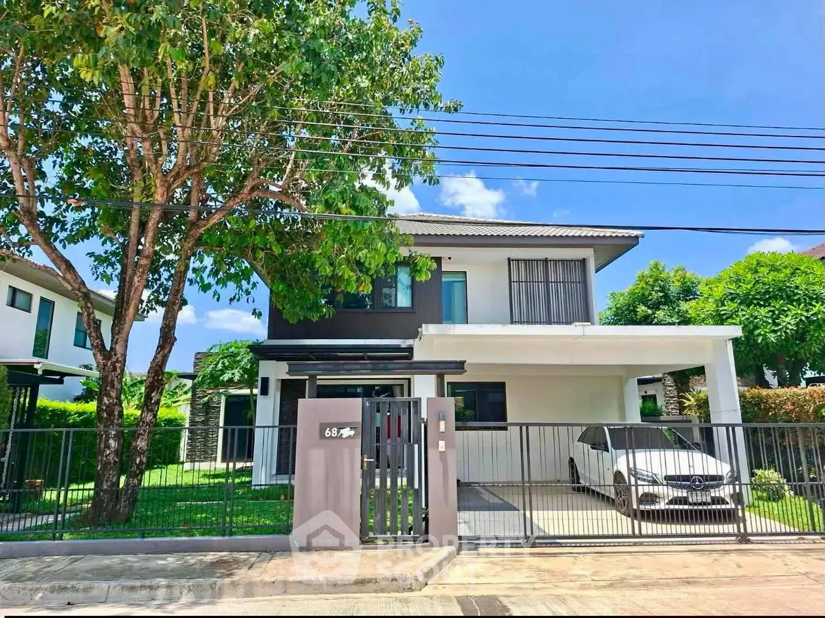 Modern two-story house with carport and lush greenery in a serene neighborhood.