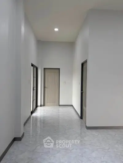 Spacious hallway with modern doors and glossy tiled flooring in a minimalist interior design.