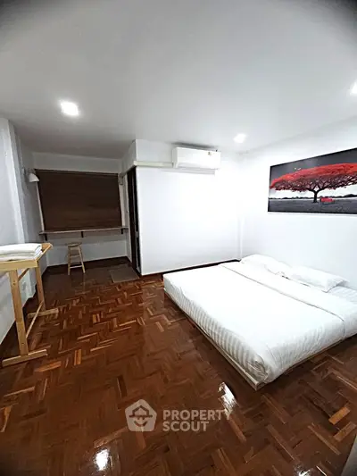 Spacious minimalist bedroom with wooden flooring and modern decor