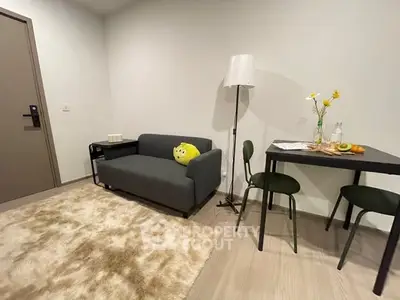 Cozy living room with modern sofa, stylish lamp, and dining table for two.