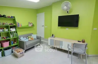 Bright living room with green walls, modern furniture, and wall-mounted TV
