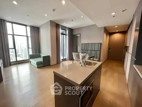 Spacious modern living room with open kitchen and large windows offering city views.