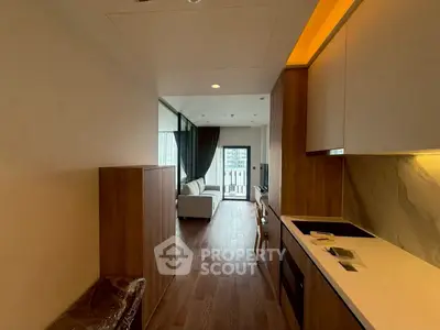 Modern apartment interior with open kitchen and cozy living area leading to balcony.