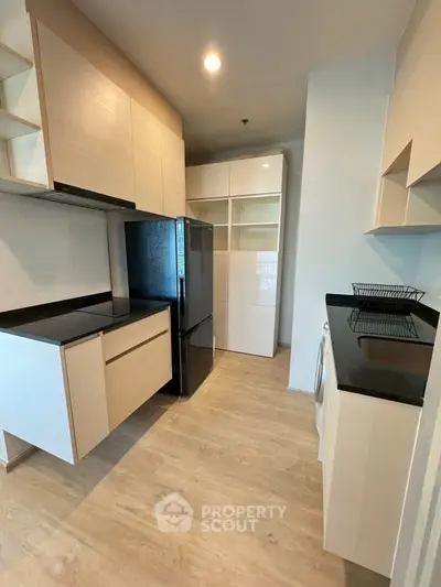 Modern kitchen with sleek black countertops and spacious cabinetry in a contemporary apartment.