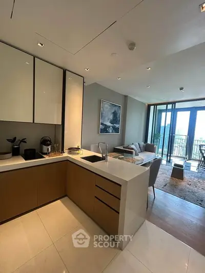 Modern open-layout kitchen with sleek design and spacious living area, featuring large windows and a balcony view.