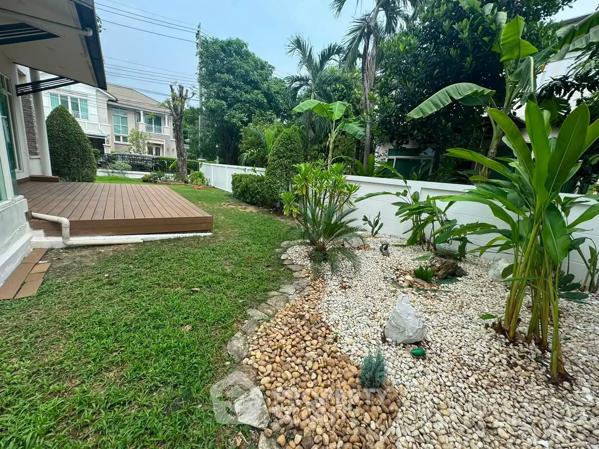 Charming garden with lush greenery and wooden deck in a suburban home backyard.