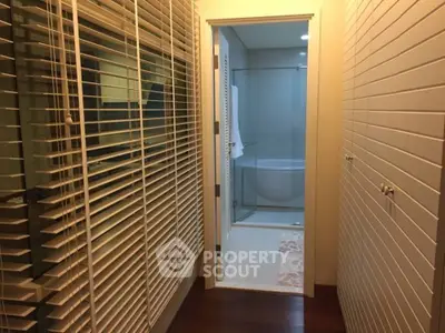 Elegant hallway leading to a modern bathroom with glass shower enclosure.