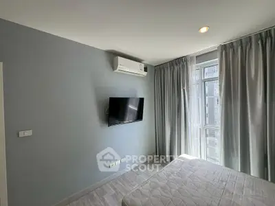Modern bedroom with natural light, featuring a wall-mounted TV and air conditioning.