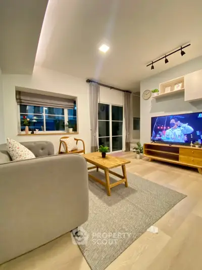 Modern living room with cozy decor and large window, featuring a stylish sofa and entertainment setup.