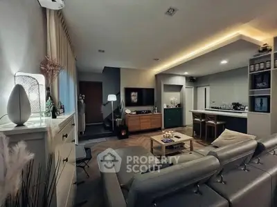 Modern living room with open kitchen, stylish decor, and cozy lighting.