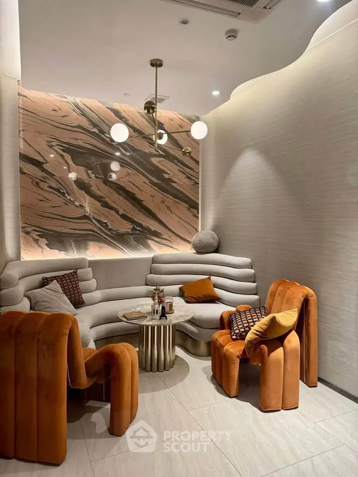 Luxurious modern living room with unique orange chairs and marble accent wall, perfect for stylish gatherings.