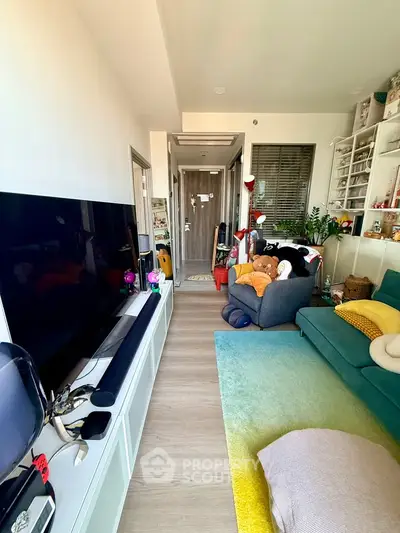 Modern living room with large TV, cozy seating, and vibrant decor in a stylish apartment.