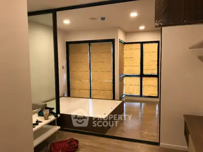 Modern bedroom with large windows and wooden flooring, under construction or renovation.