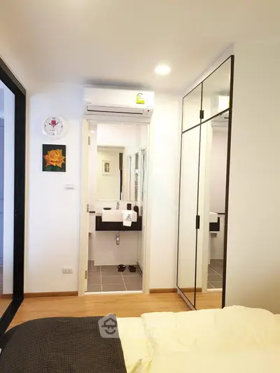 Modern bedroom with mirrored closet and ensuite bathroom in stylish apartment.