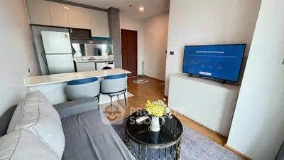 Modern living room with open kitchen, featuring sleek furniture and stylish decor in a cozy apartment.