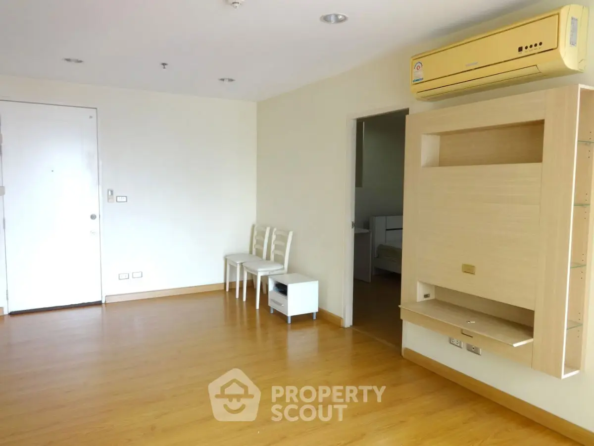 Spacious living room with wooden flooring and modern air conditioning unit.
